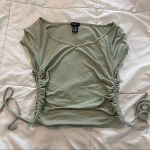 Sage green top with 2 drawstrings on the sides.